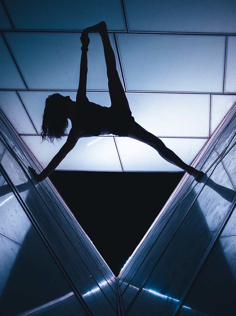 A woman in a handstand on a metal structure, illustrating the connection between physical activity and therapeutic benefits from cbt therapy