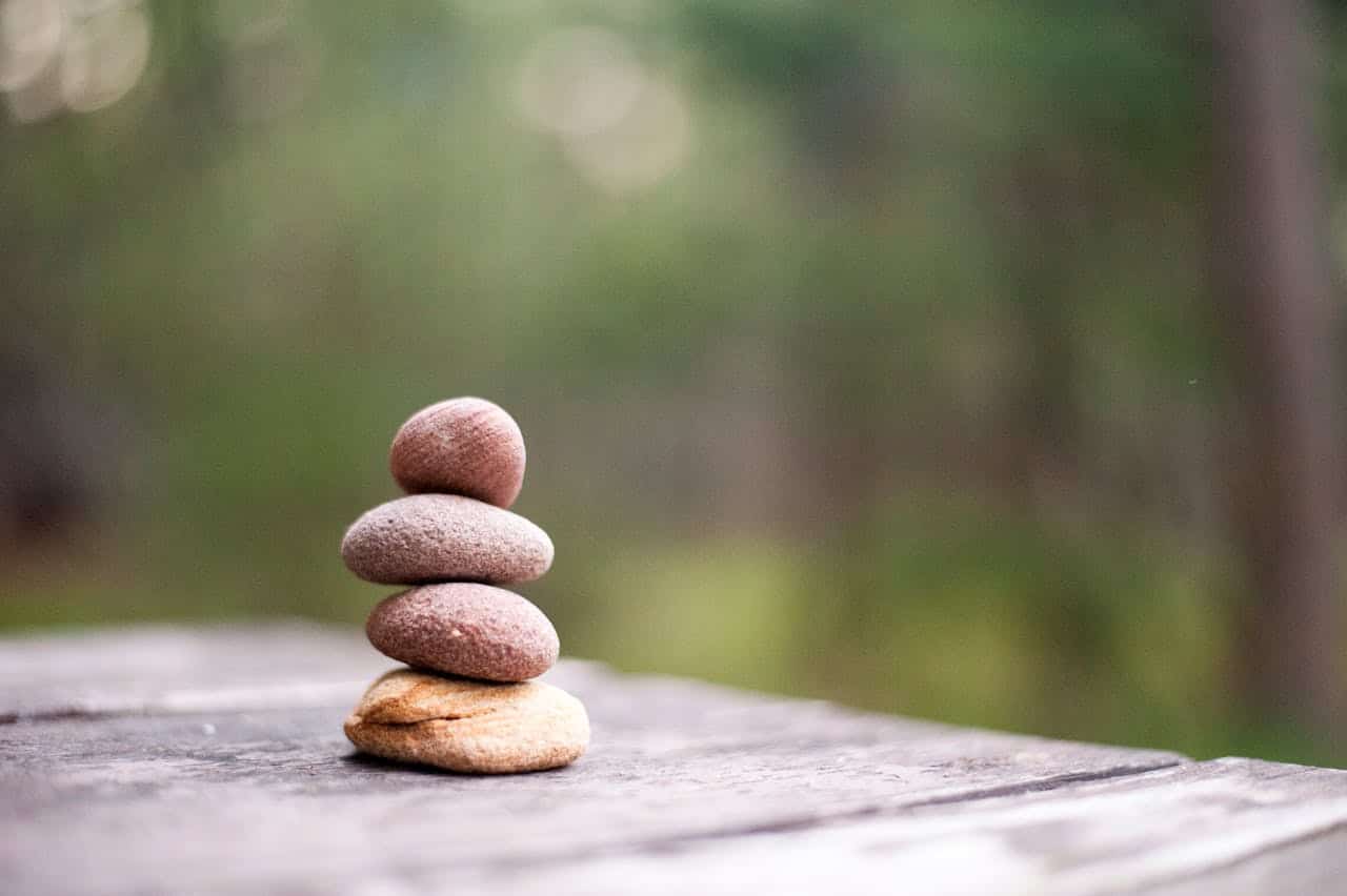 Stacked smooth pebbles on a wooden surface representing balance and mindfulness in CBT therapy.