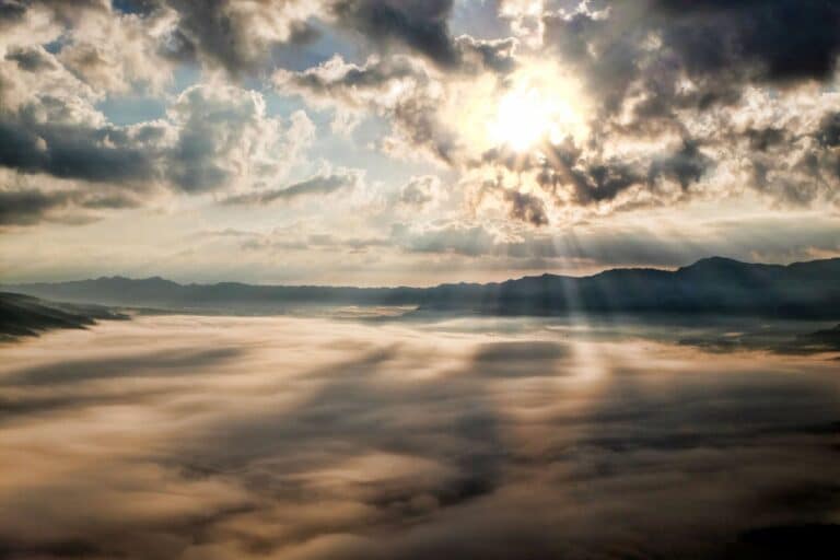 Sunlight breaking through clouds over misty mountains, symbolizing hope and clarity in cognitive behavioral therapy.