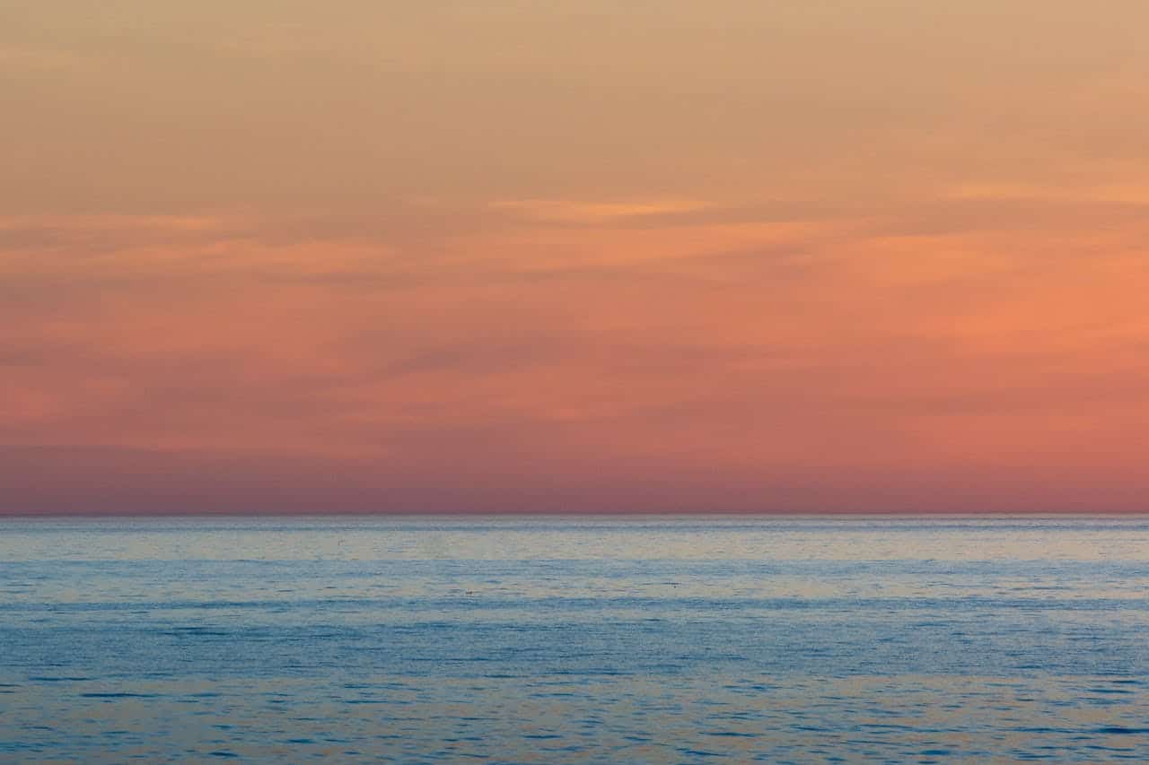 Soft pastel sunset over a calm ocean, symbolizing emotional overwhelm and the pursuit of inner peace.