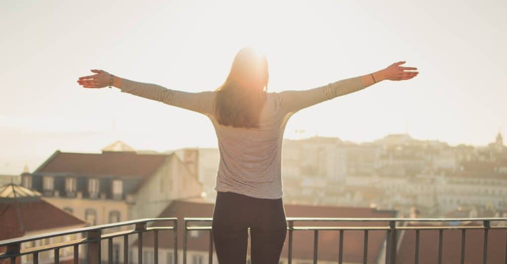 Woman standing with open arms in sunlight representing mental clarity and emotional relief through CBT