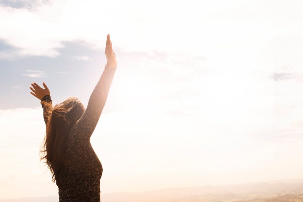 Person standing with arms raised, symbolizing emotional awareness and mental clarity through CBT and mindfulness practices