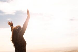 Person standing with arms raised, symbolizing emotional awareness and mental clarity through CBT and mindfulness practices