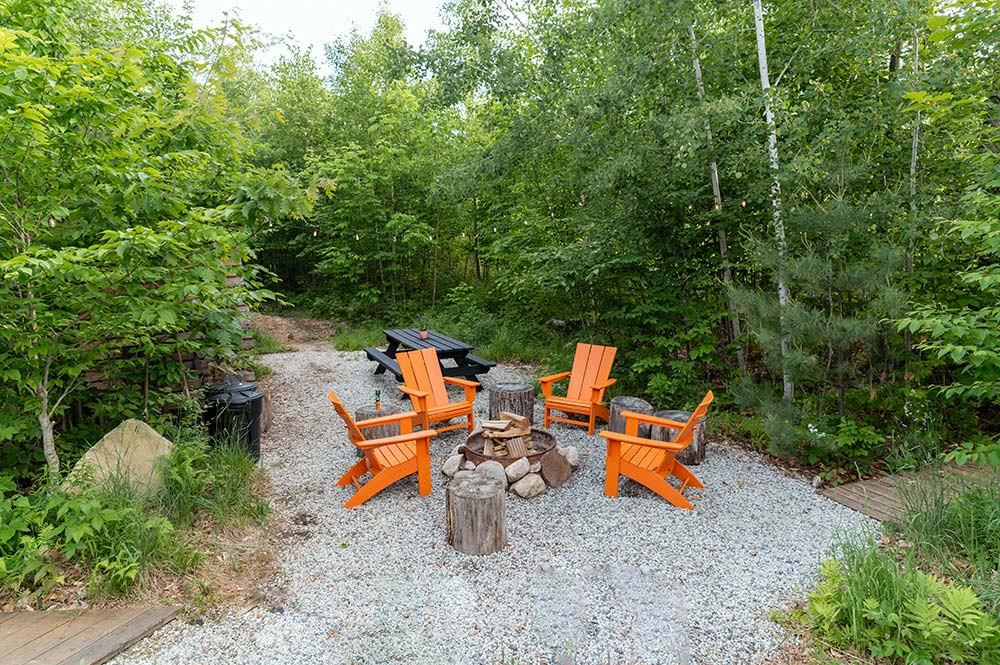 outdoor fire pit with orange chairs and a picnic table