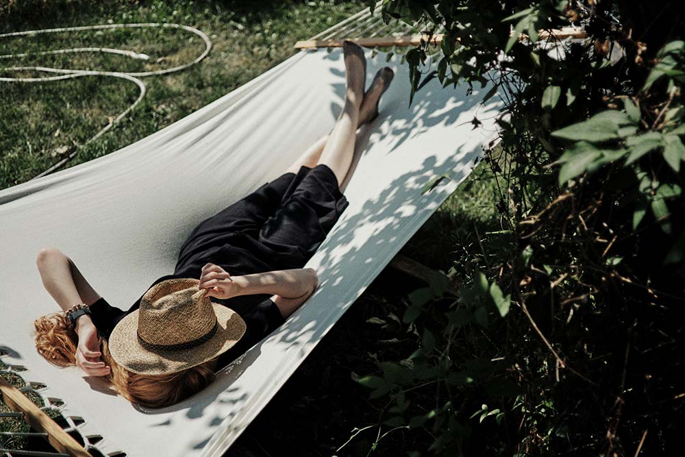 a man laying in a hammock with a hat on